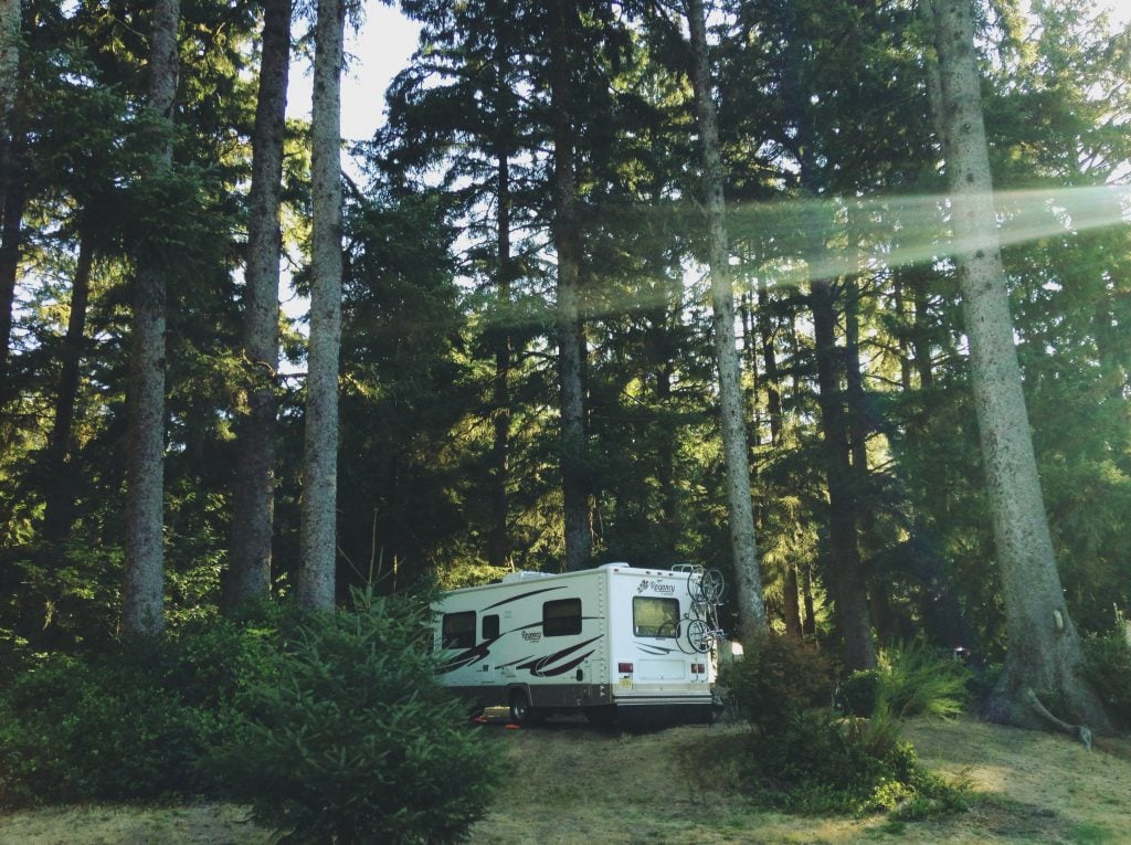 RV boondocking in the forest with sun shining through the trees