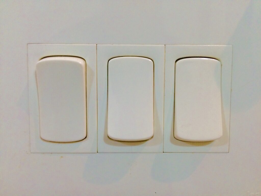 A set of three light switches. When wondering how long will RV battery last boondocking, you can make it last longer by turning off the lights.
